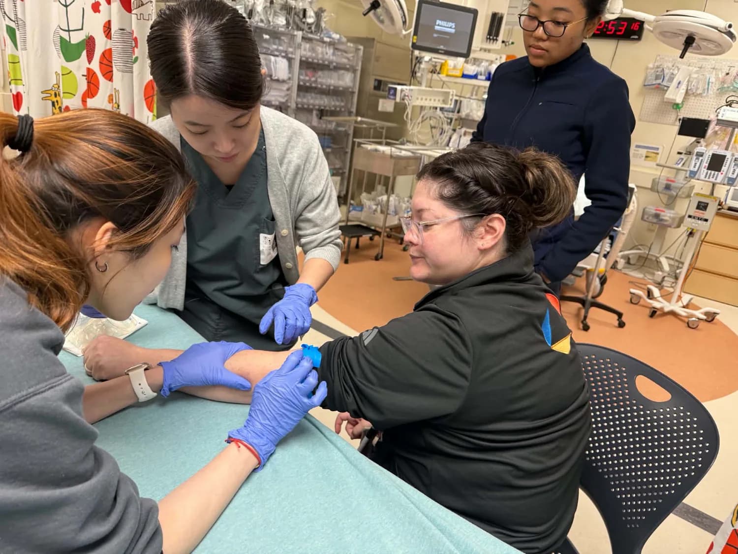 Participants practicing a hands-on clinical technique together in a training room.