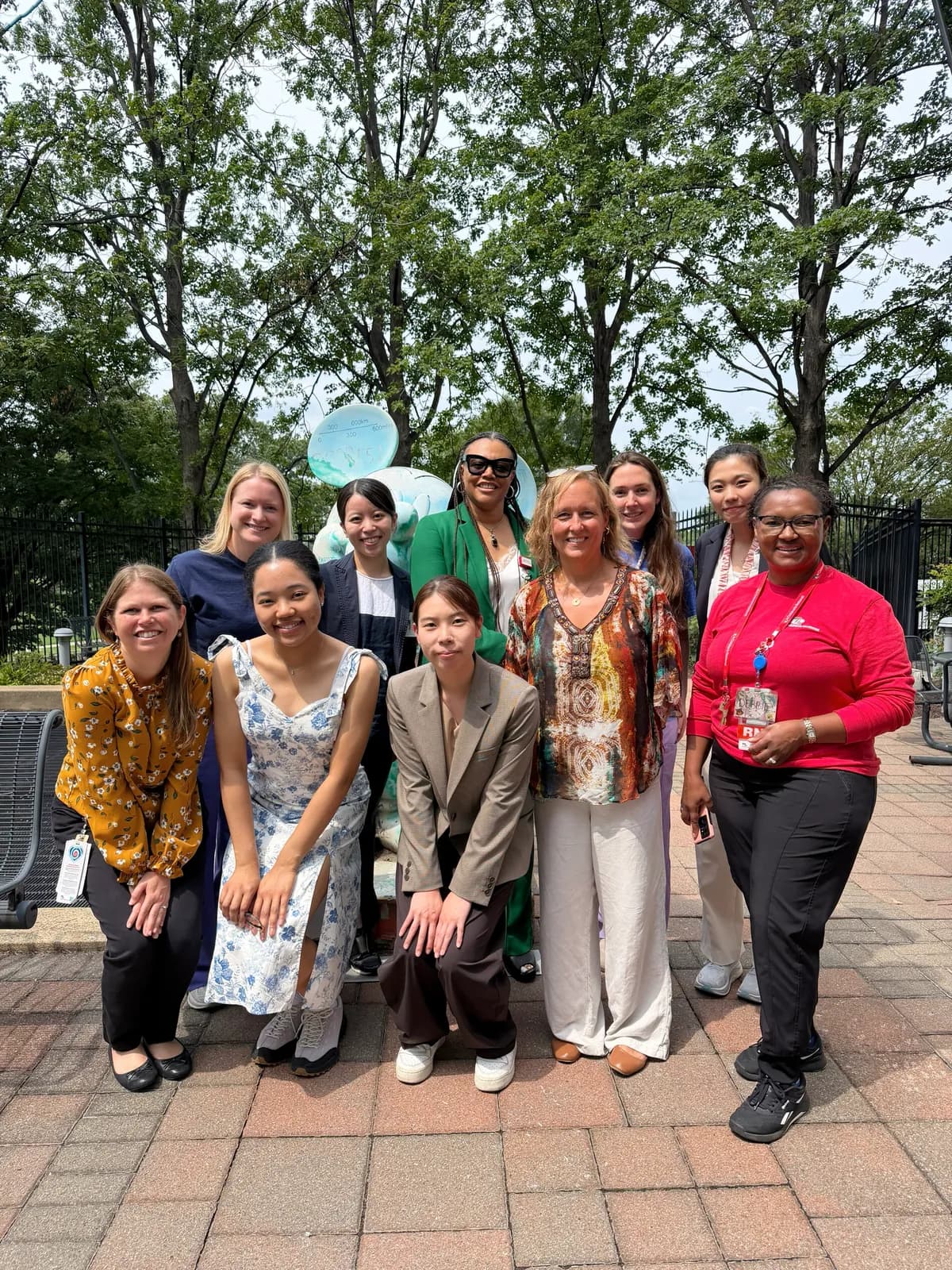 Participants at the 2026 Network Lunch posing together outdoors beneath leafy trees.